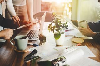 Foto: Tisch mit Personen und Laptop