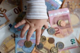 Foto: Babyhand und Geld